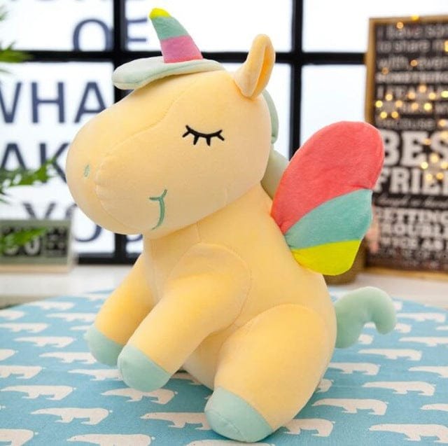 Plush unicorn toy with colorful horn and wings on a blue blanket