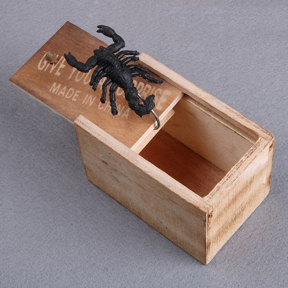 Wooden box with a black scorpion figurine on a gray background