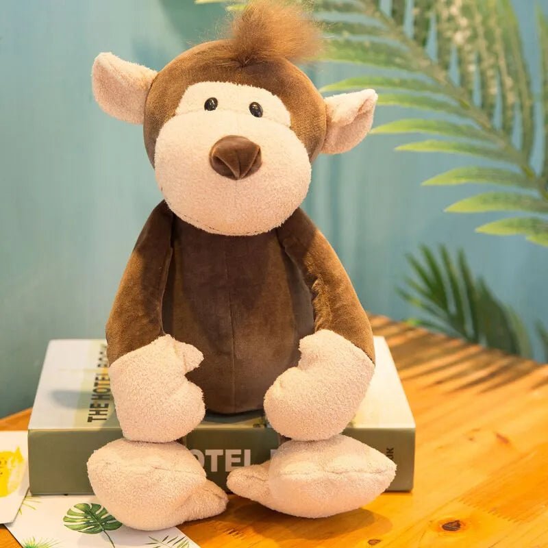 Plush monkey toy on a book with a blurred green plant background