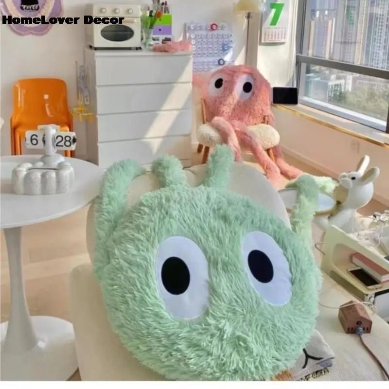 Green plush toy with googly eyes on a table in a room with decor elements.