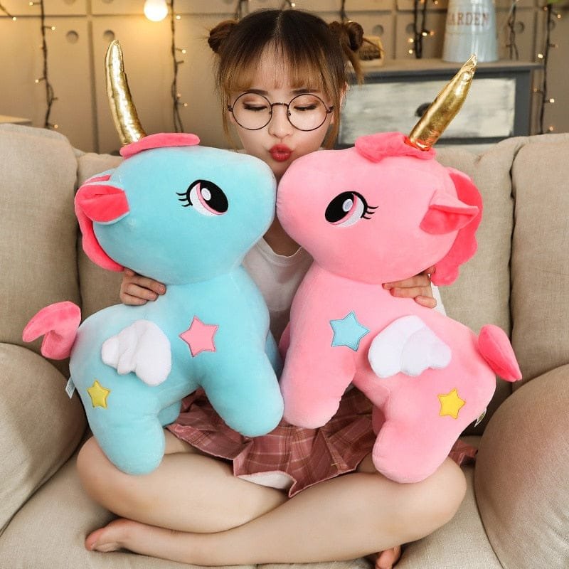 Person holding two colorful plush toys resembling ponies on a couch.