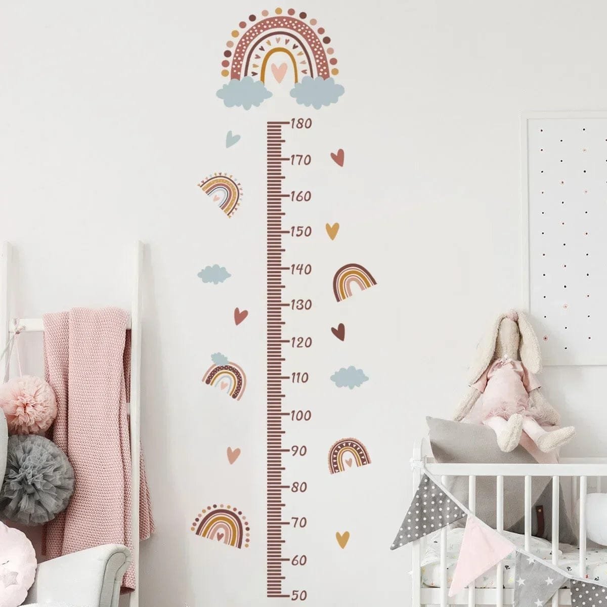 Children's growth chart with rainbow and cloud design on a white wall in a nursery.