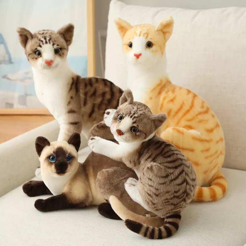 Four plush cat toys in different breeds on a white surface.