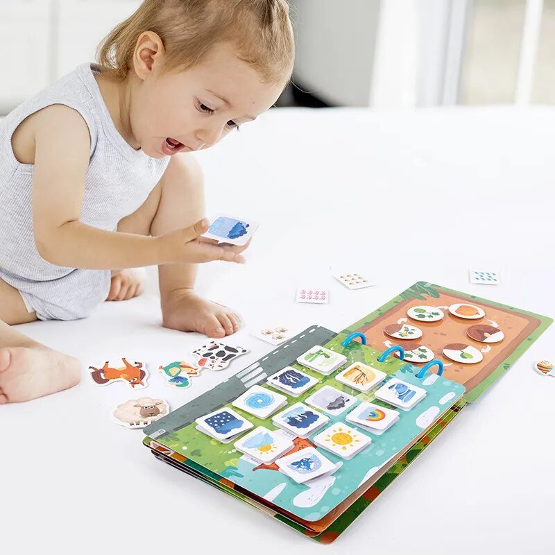 Child playing with a colorful educational book on a white surface