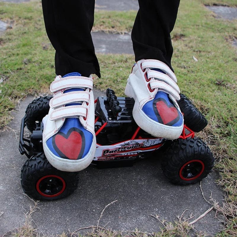 Person wearing white sneakers with red and blue hearts on a small off-road vehicle.