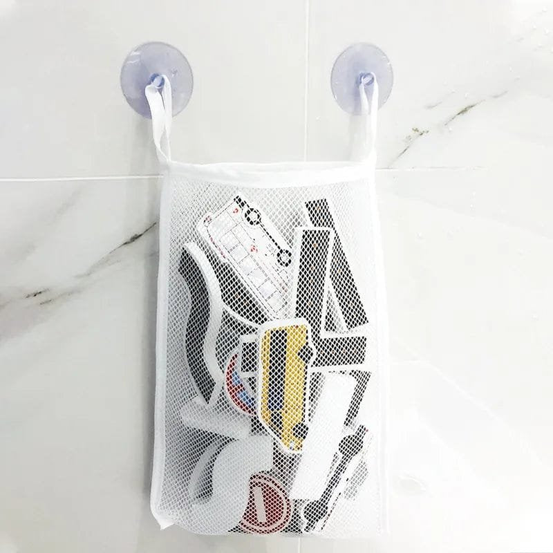 Mesh laundry bag with sneakers inside, hanging on a white wall with suction cups.