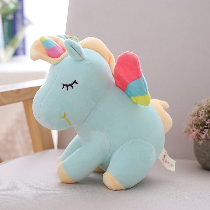 Plush toy unicorn with a rainbow mane on a light surface.