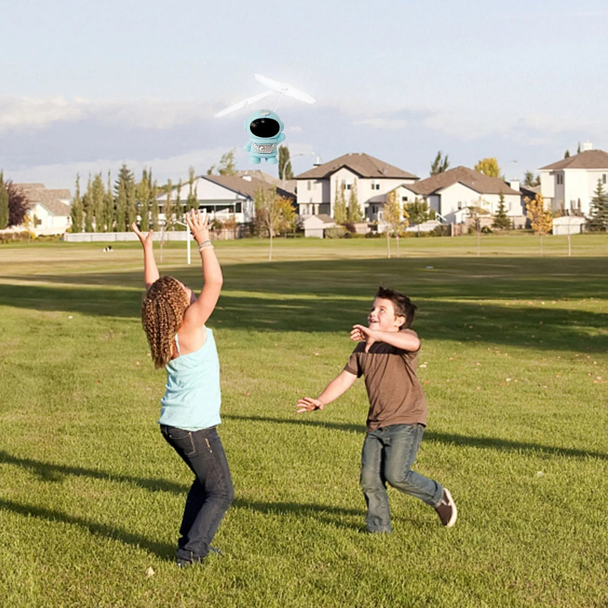 Two children playing with a disc on a grassy field with houses in the background