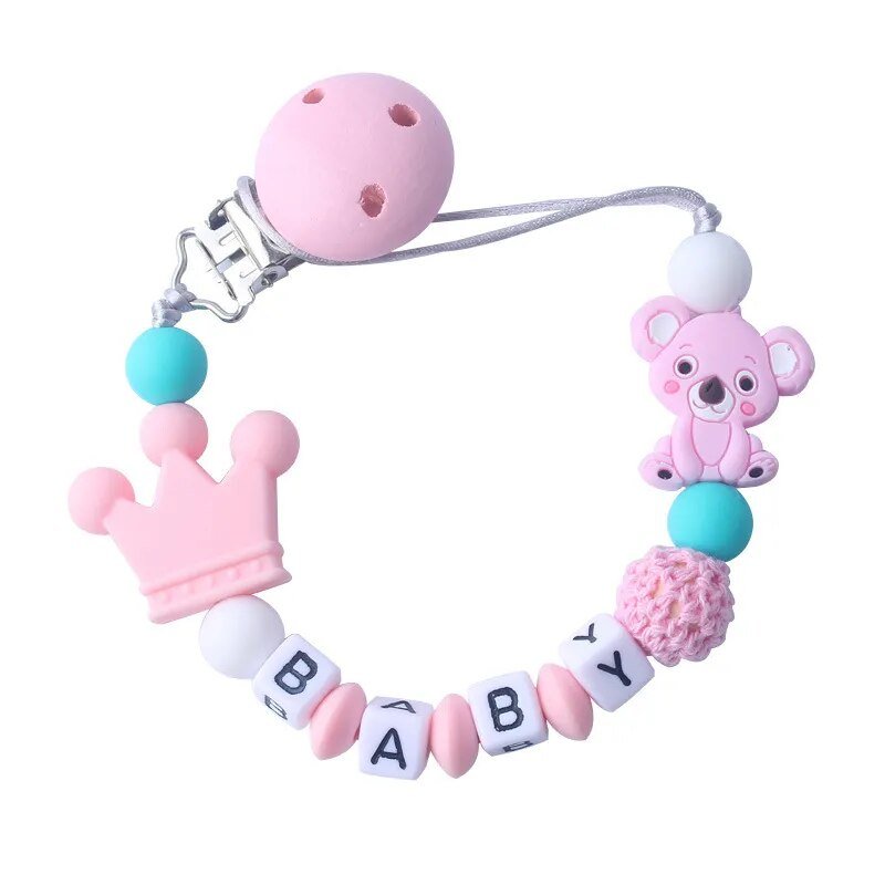 Baby teether with pink bear, blue ball, and crown design on a white background
