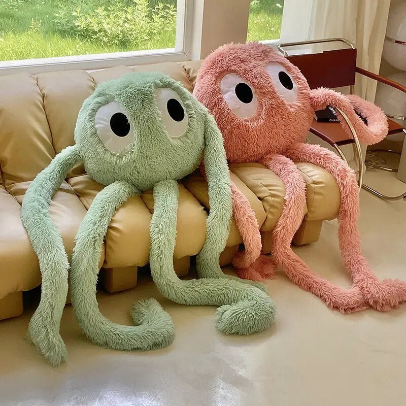Two plush octopus toys, one green and one pink, sitting on a beige couch.