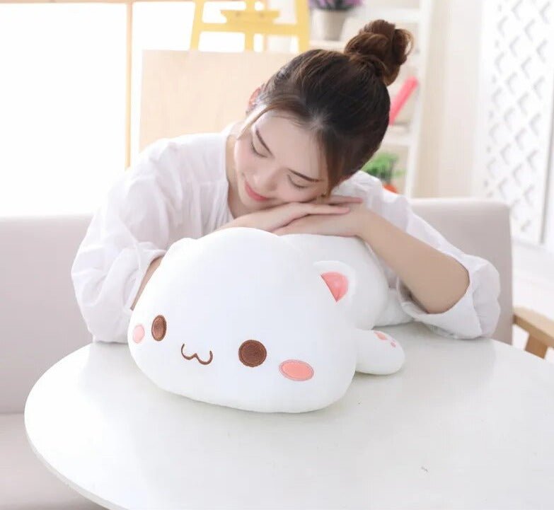 Woman sitting on a couch with a large, cute plush toy resembling a cat.