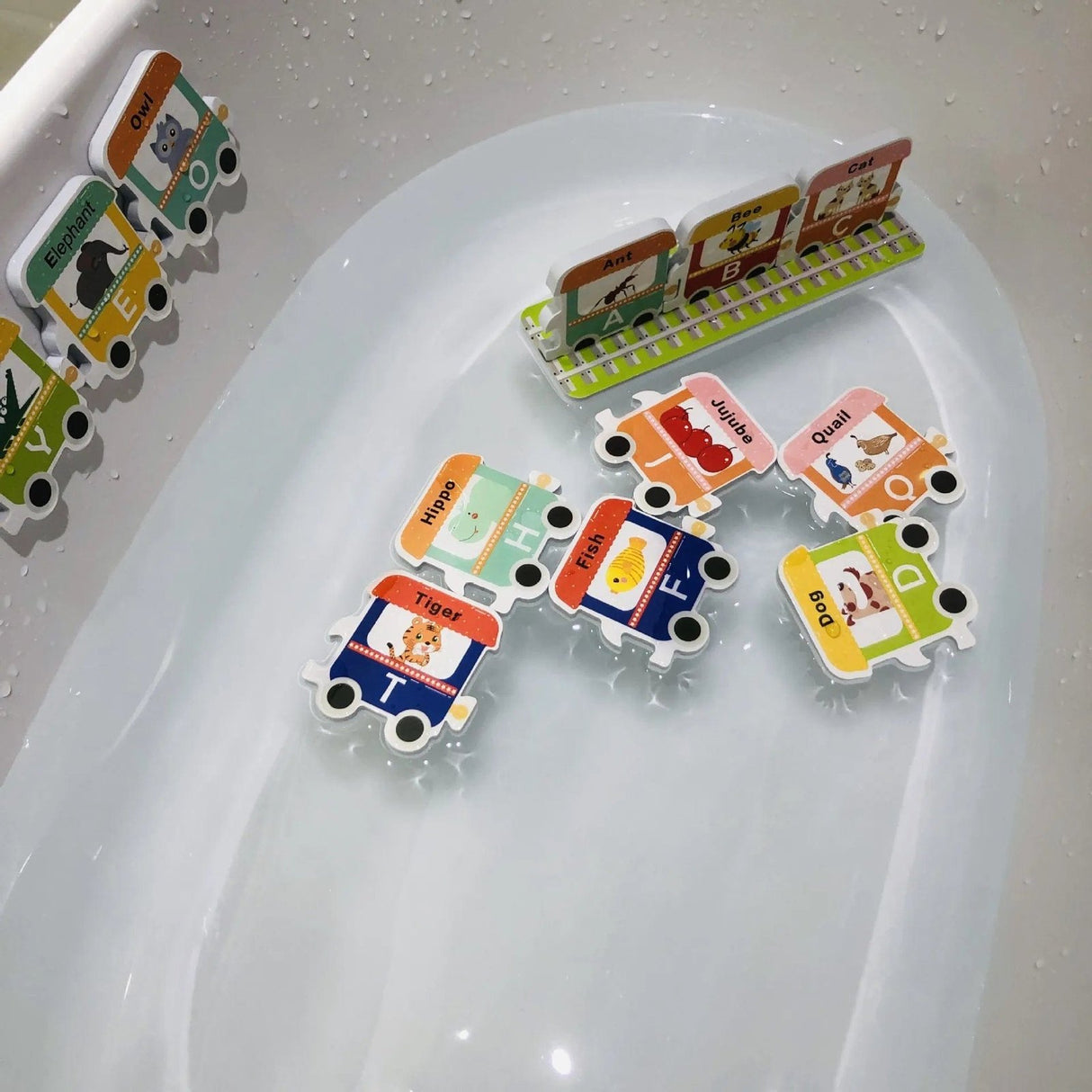 Colorful educational bath toys shaped like trains with animal illustrations on a white surface.