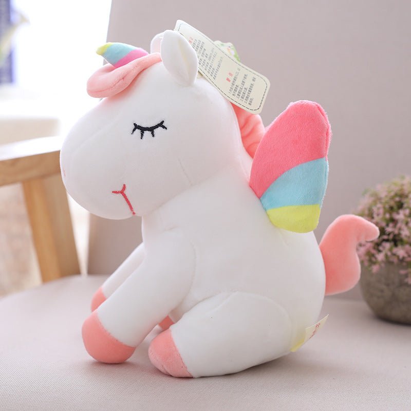 Plush unicorn toy with a rainbow-colored horn and pink mane on a light surface.