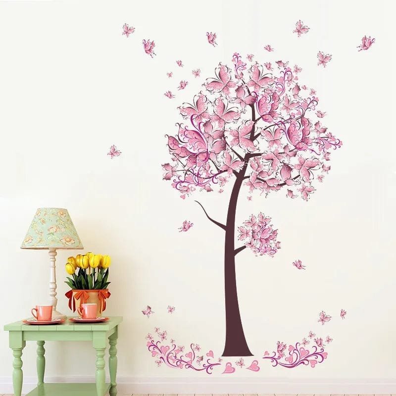 Wall decal of a pink floral tree on a white wall with a green table and lamp in the foreground.