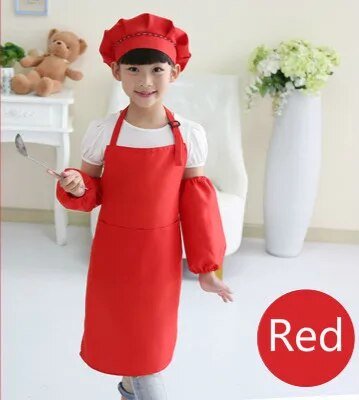 Child wearing a red apron and chef hat in a room with a teddy bear and flowers.