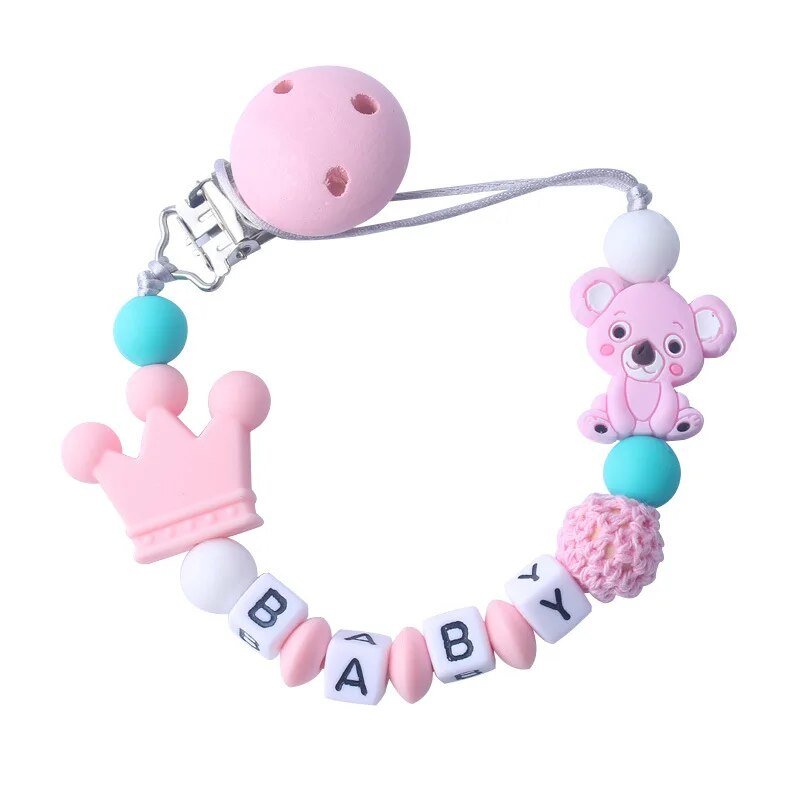 Baby teether with pink bear, blue ball, and crown design on a white background