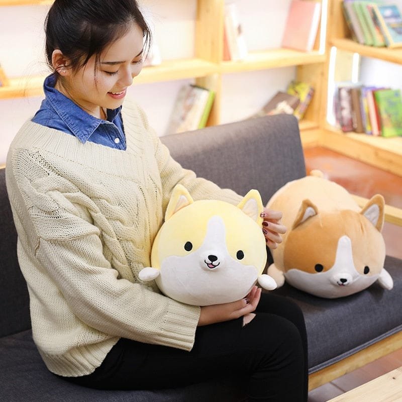 Person holding two plush dog toys on a couch in a cozy room.
