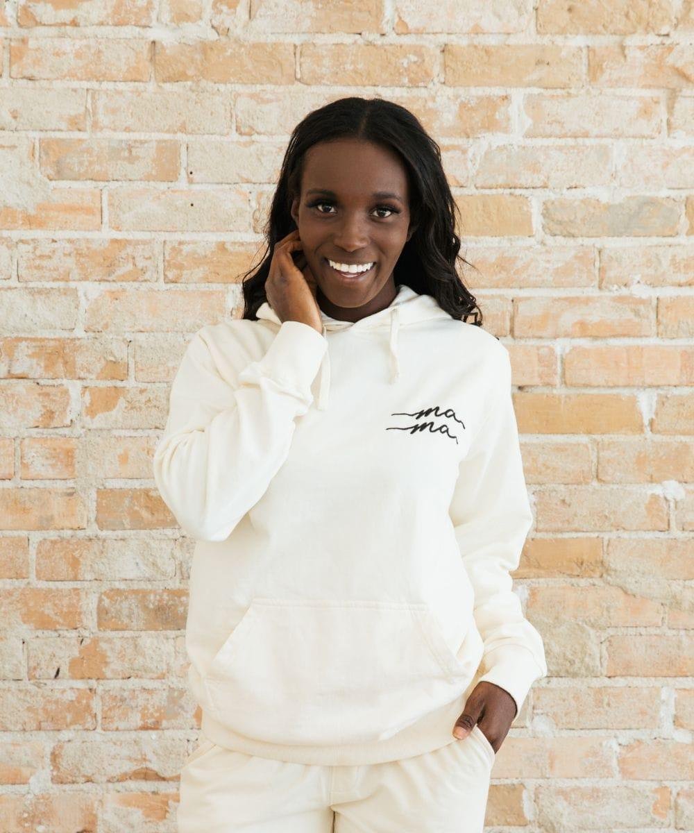 Person wearing a white hoodie with text against a brick wall