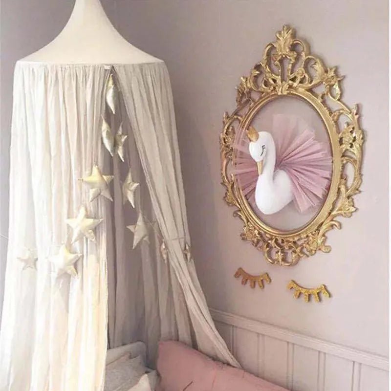 Decorative wall art with a swan sculpture in a gold frame on a light pink wall.