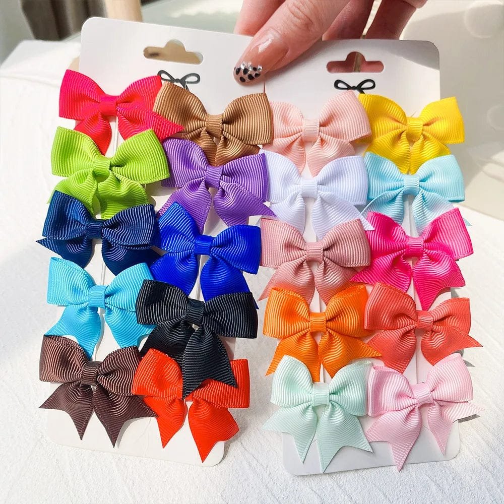 Assorted colorful hair bows on a white card held by a hand.