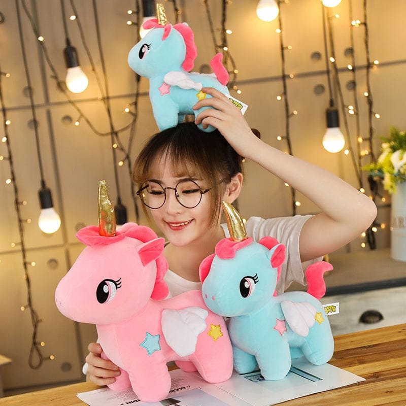 Person holding two colorful unicorn plush toys.