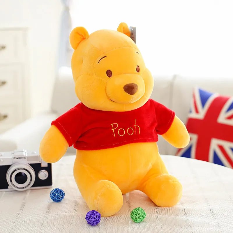 Plush toy bear wearing a red shirt with 'Pooh' on it.