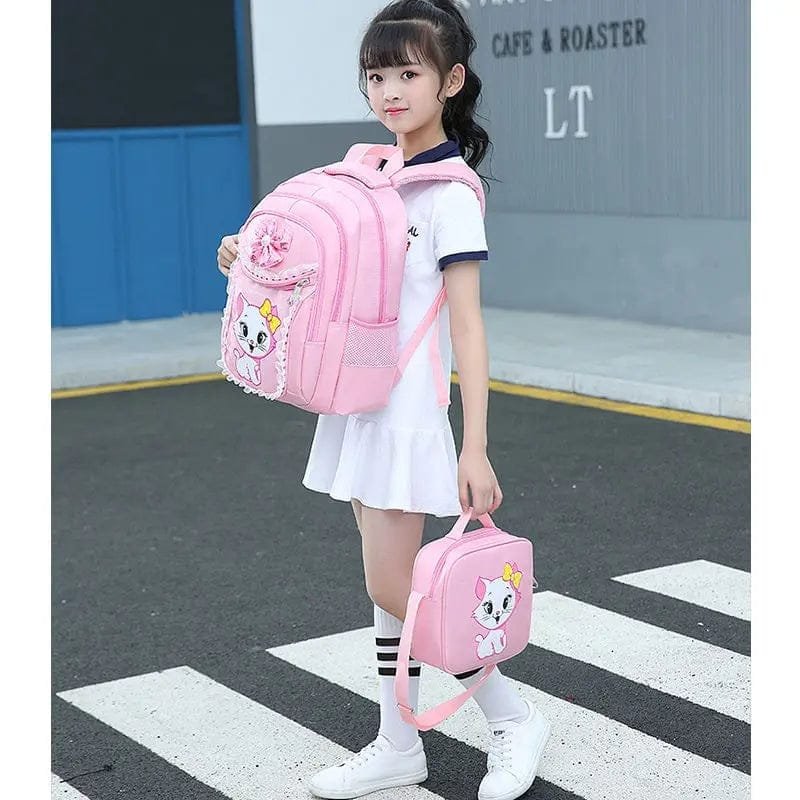 A girl holding a pink backpack and lunch bag with a cartoon character