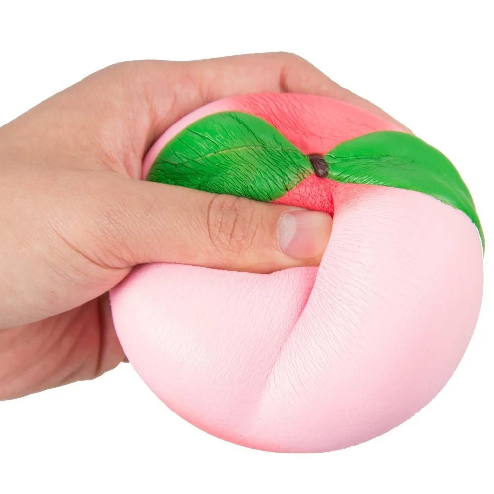 Hand holding a pink and green stress ball against a white background