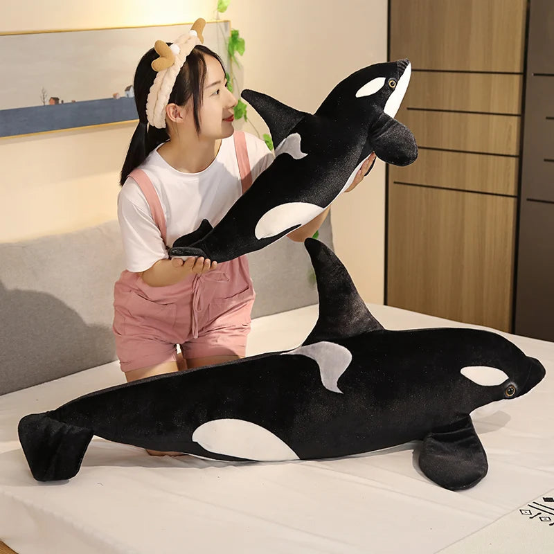 Child holding a large plush orca whale toy in a bedroom setting