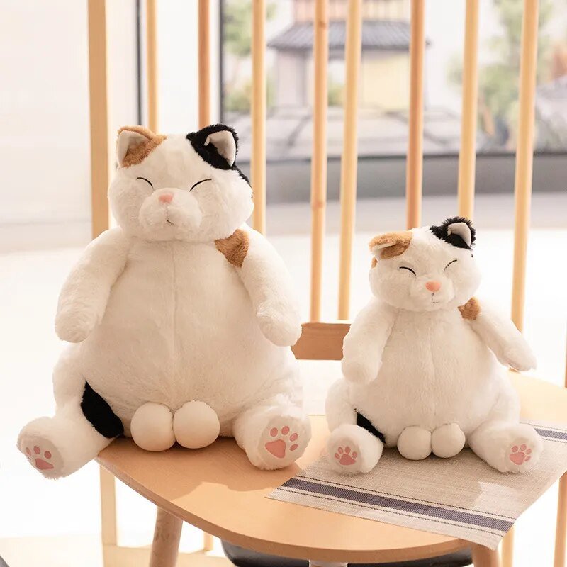 Two plush cat toys sitting on a chair