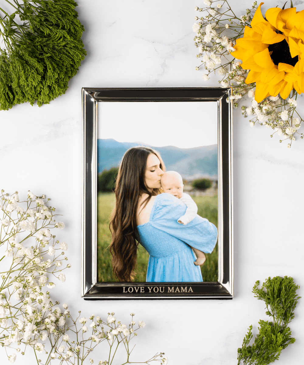 Framed photo of a woman holding a baby with decorative flowers.