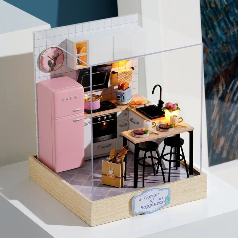 Miniature model of a kitchen with pink refrigerator and various appliances on a clear stand.