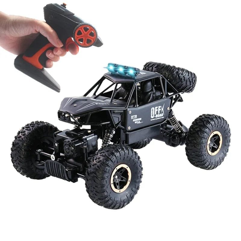Black remote control monster truck with large wheels and a hand holding a remote control.