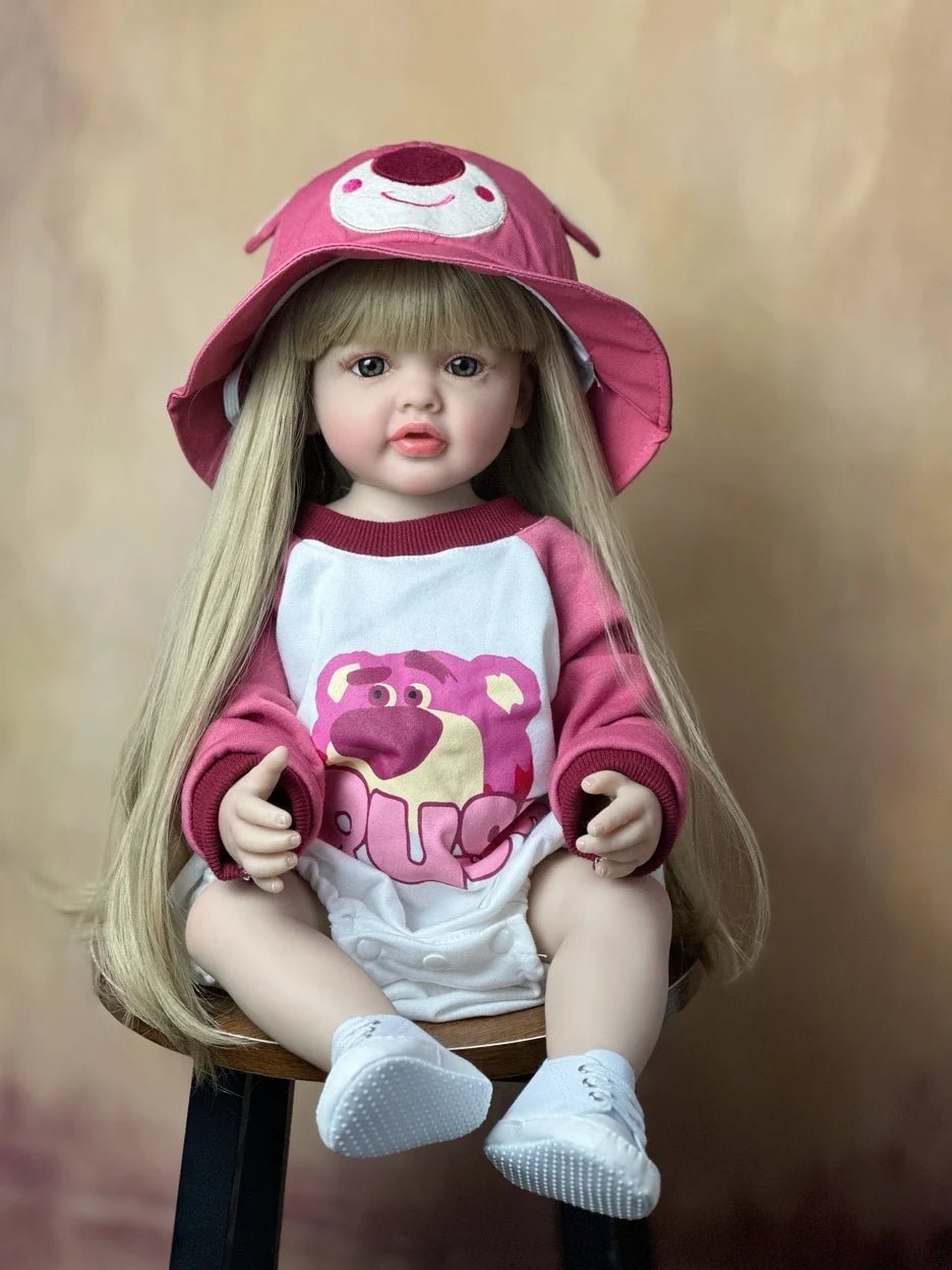 Doll wearing a pink cap and shirt with a bear design on a brown background