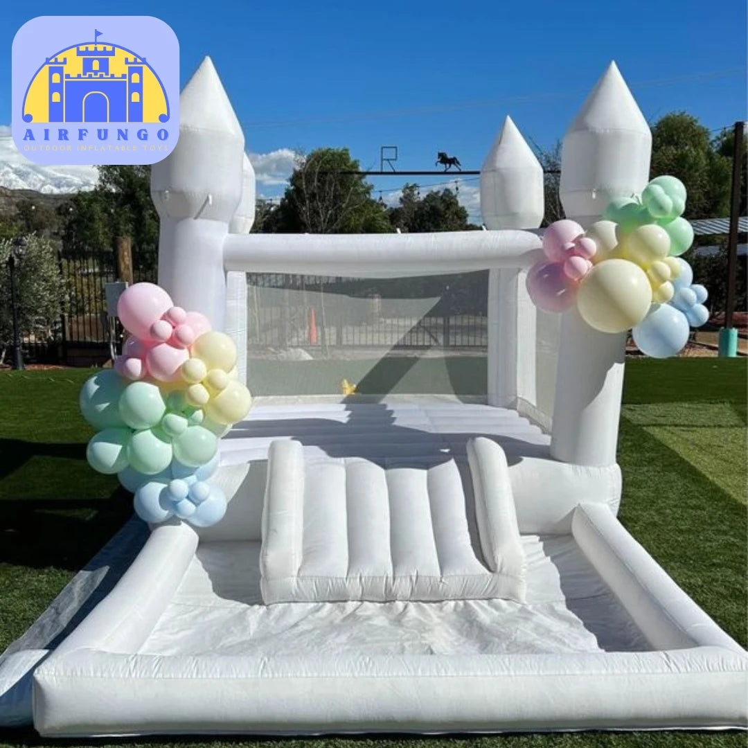 Inflatable castle with pastel balloon decorations on a grassy field.