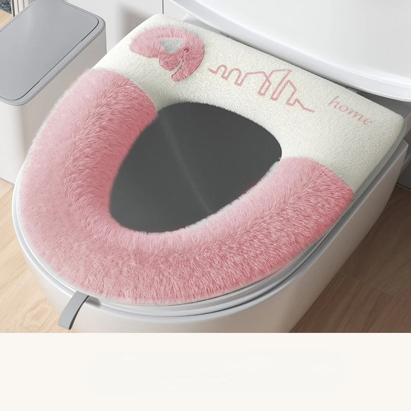 Pink and white toilet seat cover with 'home' text on a toilet.