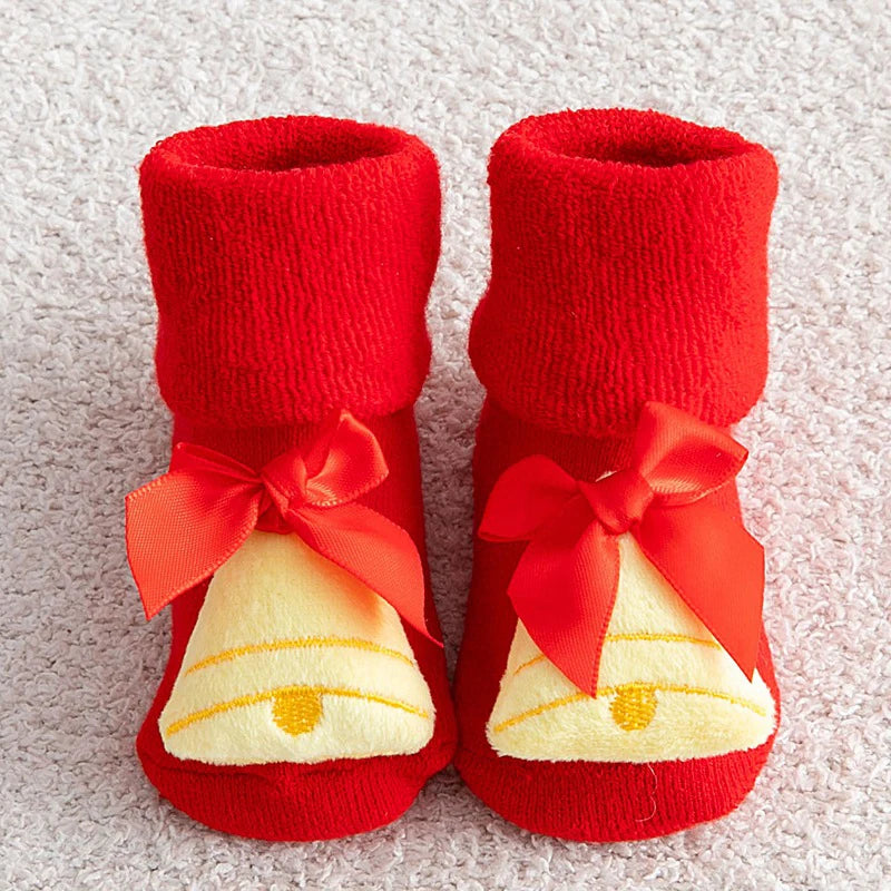 Red baby booties with white bell design and red bows on a light gray background