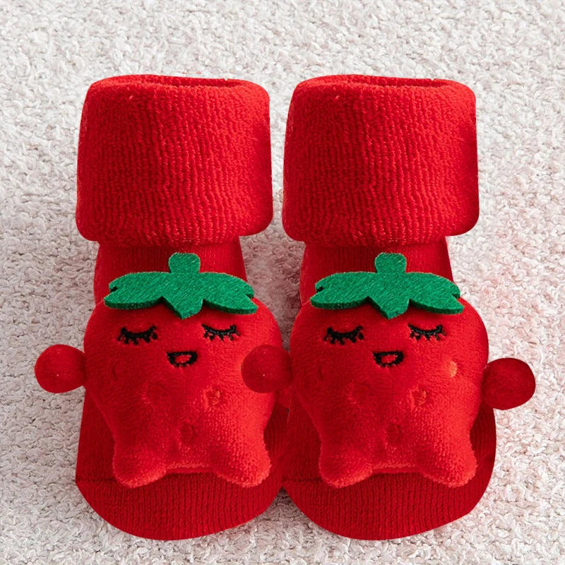 Red baby booties with tomato design on a textured surface