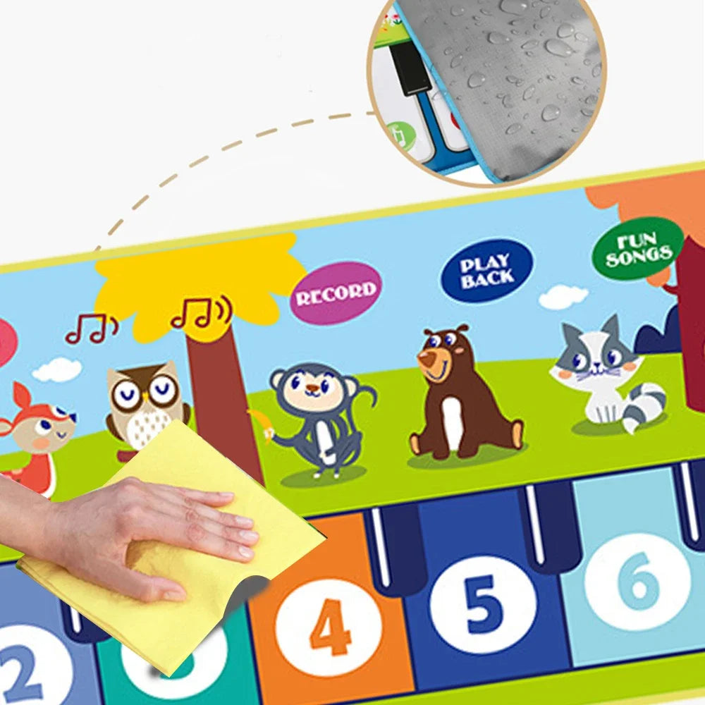 Children's musical play mat with cartoon animals and numbers, being wiped by a hand.