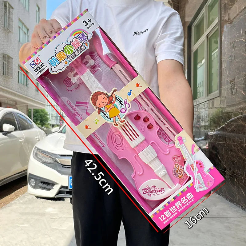 Person holding a pink toy violin set in packaging with measurements displayed.