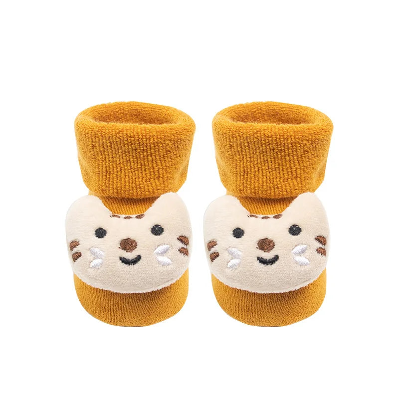 Pair of mustard yellow baby booties with cat face design on a white background