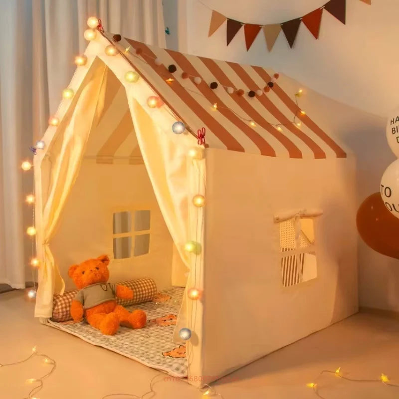 Children's play tent with striped roof and teddy bear inside, decorated with string lights.