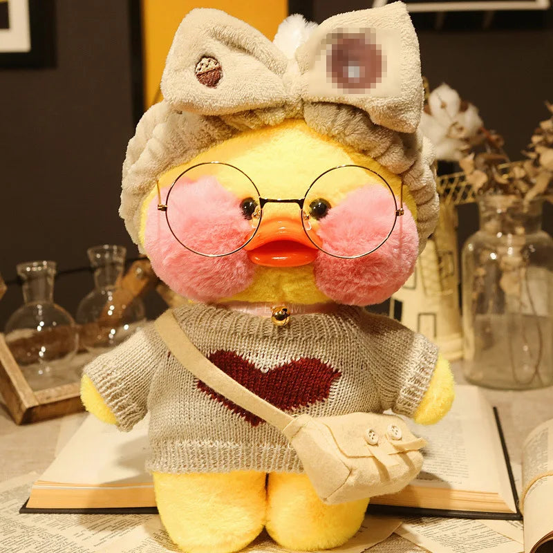 Plush toy duck wearing glasses, a sweater with a heart, and a headband with a bow on a surface.