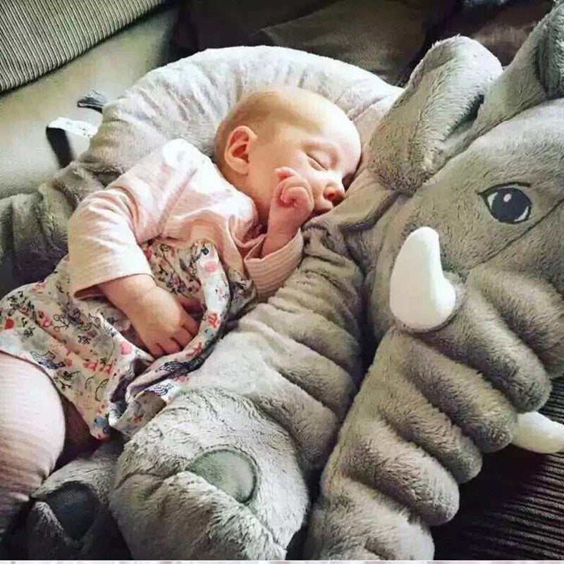 Baby sleeping on a large plush elephant toy.