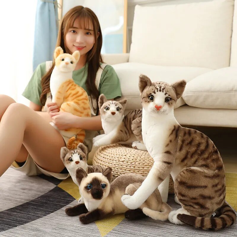 Woman sitting on the floor with a variety of cat-shaped plush toys in a home setting.