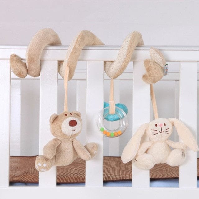 Baby crib with hanging toys including a teddy bear, bunny, and teething ring.