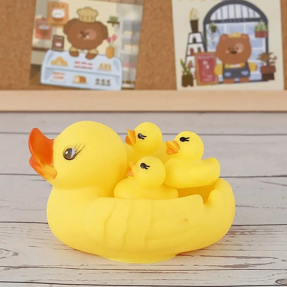 Yellow rubber duck with three smaller ducks on a wooden surface.