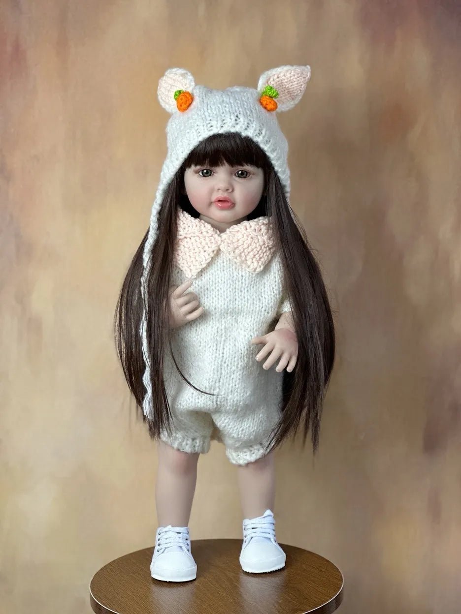 Doll wearing a knitted outfit with bear ears and a bow tie on a wooden stand