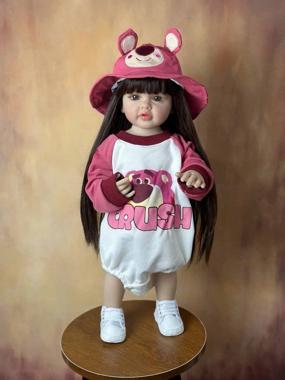 Child's doll wearing a pink and white outfit with a hat on a wooden stool