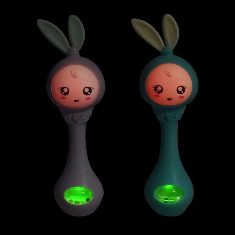 Two colorful baby rattles with glowing green bases on a black background